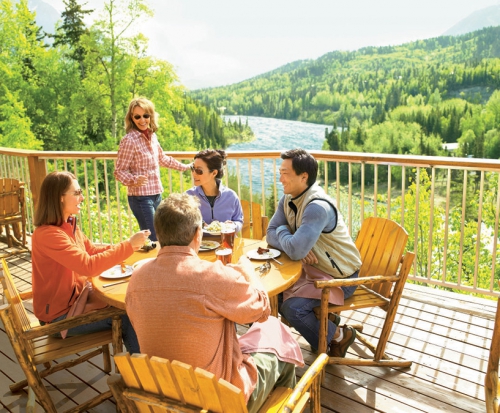 Guests dining on a deck overlooking the river at the Kenai Princess Lodge